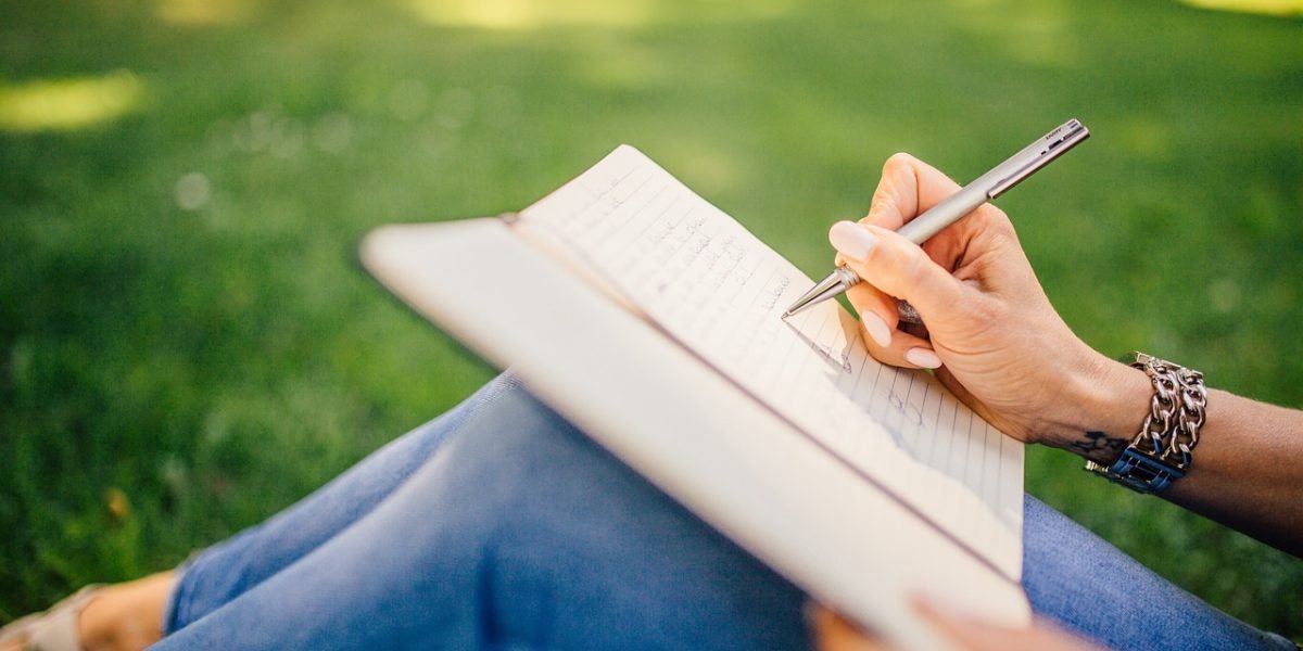 A person writing in a journal, illustrating a practical exercise for self-reflection and articulating emotions.
