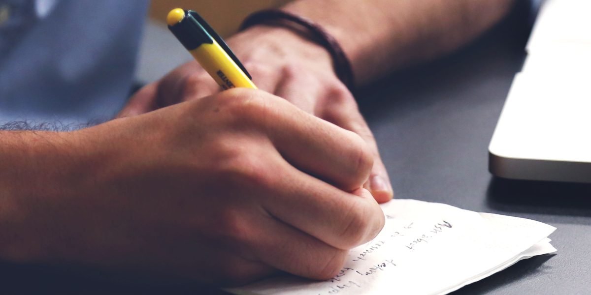 A person writing in a journal or planner, illustrating active engagement in self-care practices.