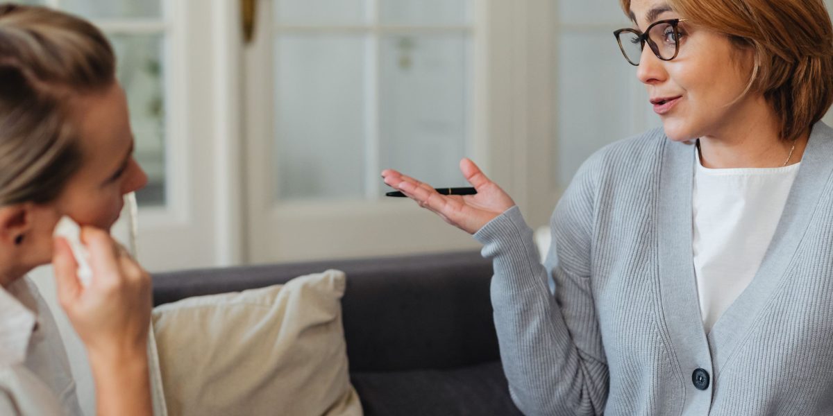 Two individuals engaged in a supportive conversation, symbolizing a therapeutic discussion around mental health strategies.