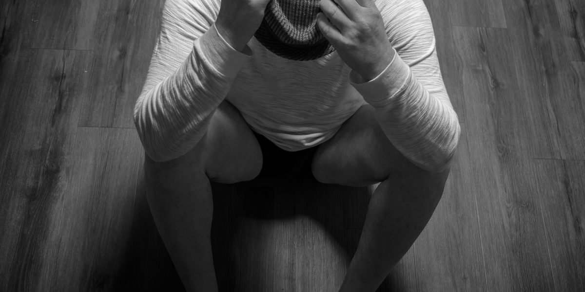 A person looking withdrawn or deep in thought, representing feelings of isolation and confusion that can accompany early signs of delusions.
