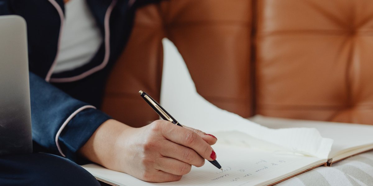 An individual focused on writing or planning, representing the active process of incorporating self-care and coping skills into a daily routine.