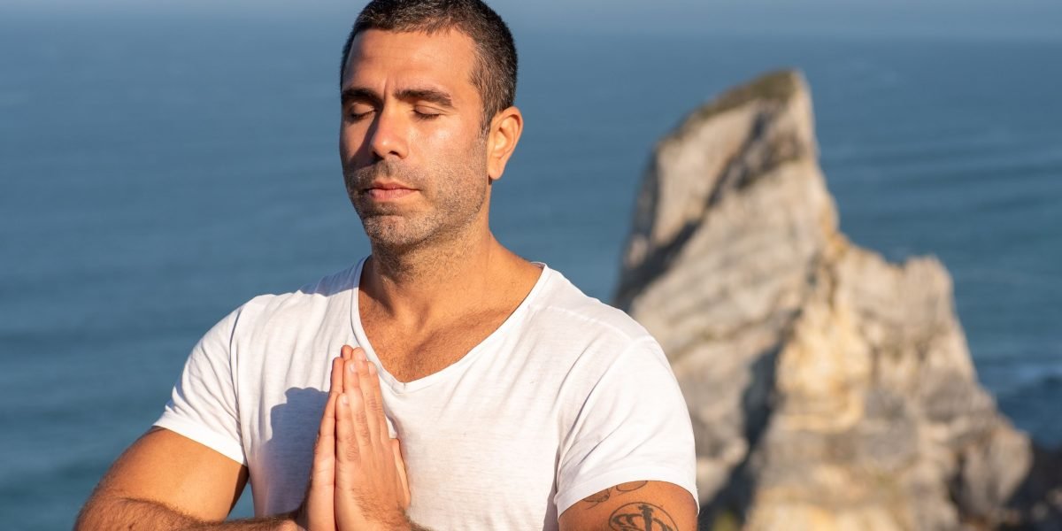 A person with a calm expression, demonstrating a deep breathing exercise for anxiety relief in a serene setting.
